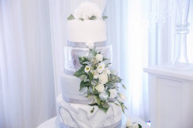 Güzel düğün pastası çiçeklerle süslenmiş. Gümüş ve beyaz renk