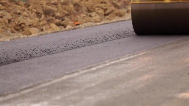 Yeni yapılmış düz bir yolda kaldırım taşıma aracı, çarpıyor ve düzleştiriyor. Asfalt kaldıracı tamir edilen şehir yoluna asfalt uyguluyor