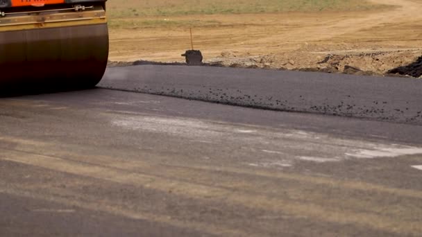 El pavimentador se mueve en una carretera plana de nueva construcción, embistiendo y nivelando. Aserradero de asfalto aplicando asfalto en la carretera de la ciudad reparada — Vídeos de Stock