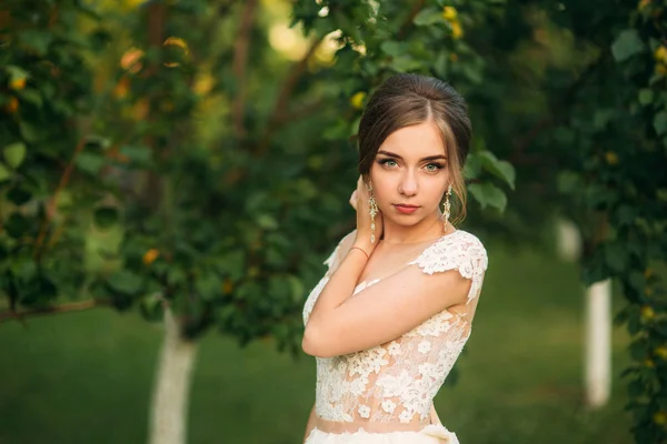 Очаровательная невеста с красивым макияжем и прической позирует для фотографа — стоковое фото