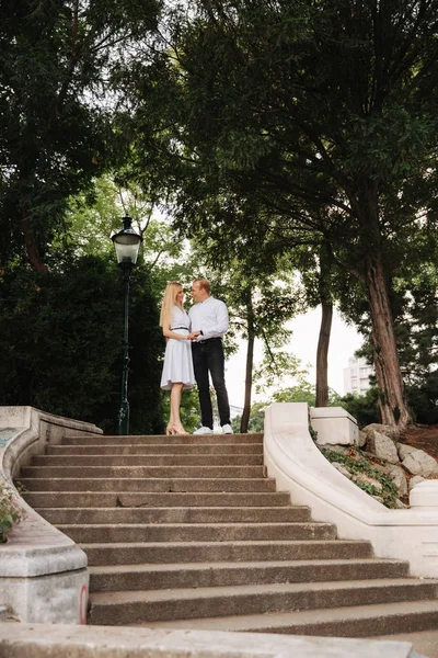 Schöne cuple stehen auf der Treppe und umarmen einander. Mann und Frau gehen im Park spazieren. Liebesgeschichte — Stockfoto