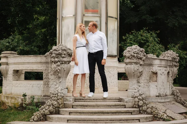 Schöne cuple stehen auf der Treppe und umarmen einander. Mann und Frau gehen im Park spazieren. Liebesgeschichte — Stockfoto