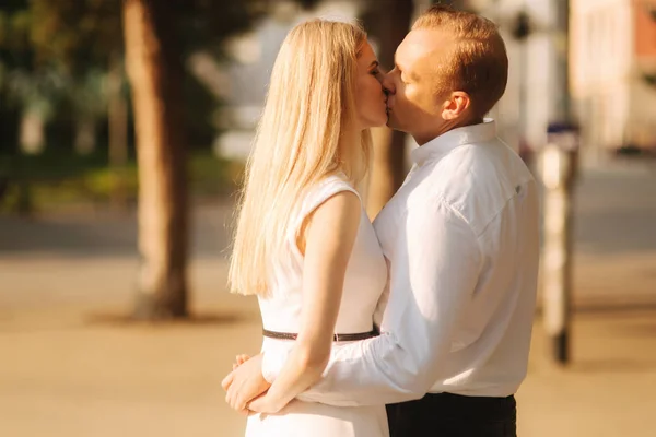 Joven pareja hermosa, marido con una camisa blanca y una esposa en un vestido caminando por el parque en verano — Foto de Stock