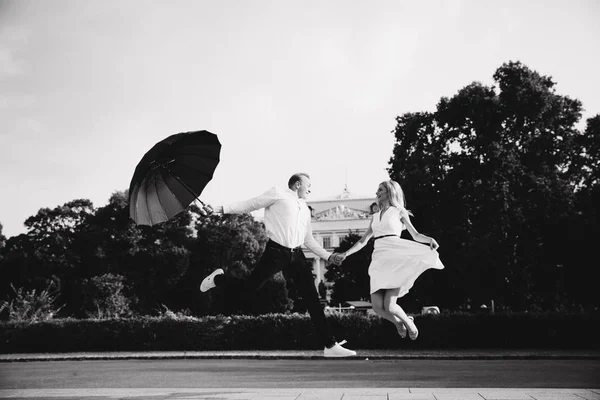 Young couple jump up with black upbrella. Lovely cuople have fun