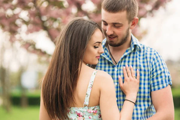 Retrato de jovem casal no clima de primavera. Árvores florescentes em torno de homem e mulher — Fotografia de Stock