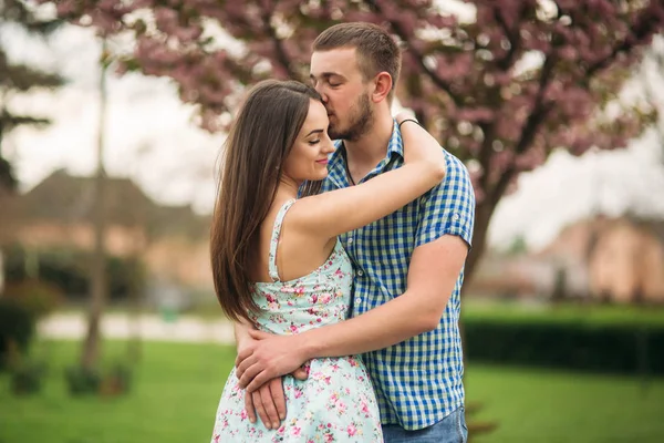 Portrét mladého páru v jarní náladě. Kvetoucí stromy kolem muž a žena — Stock fotografie