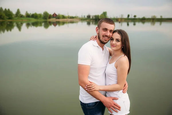 Casal apaixonado abraçar uns aos outros perto do lago — Fotografia de Stock