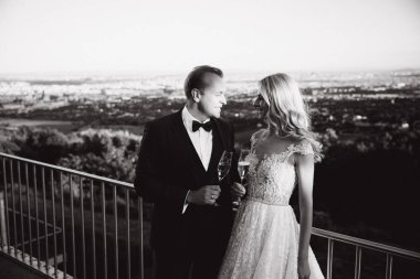 Damat ve gelin şehir ve İçecek şampanya bardağı üzerinden arka plan üzerinde durmak. Kodes gözlük