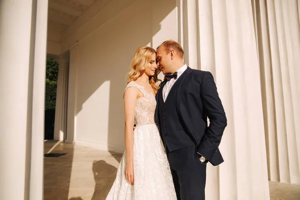 Uomo e donna in abito da sposa si trovano vicino al grande pilastro — Foto Stock