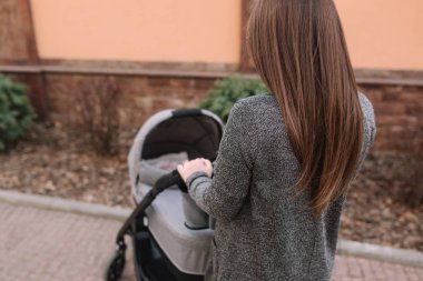 Genç Anne, Bebek arabası içinde yenidoğan bebeği ile yürüyor. Gri bir Pram. Güzel anne içinde Sunglasses