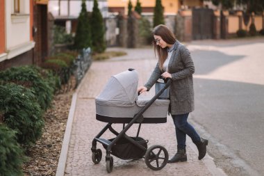 Genç Anne yürümek ile kız içinde Stroller. Annem bebeği önemsiyor. Anne Puset için bakmak ve bebek uyku yardım