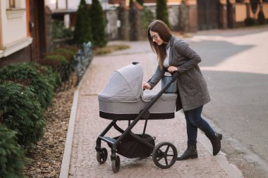 Genç Anne yürümek ile kız içinde Stroller. Annem bebeği önemsiyor. Anne Puset için bakmak ve bebek uyku yardım