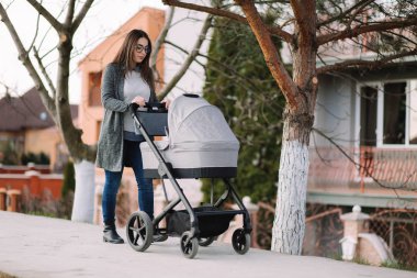 Parkta puset ile yürüyüş Genç Anne. Bebek ile şık Anne