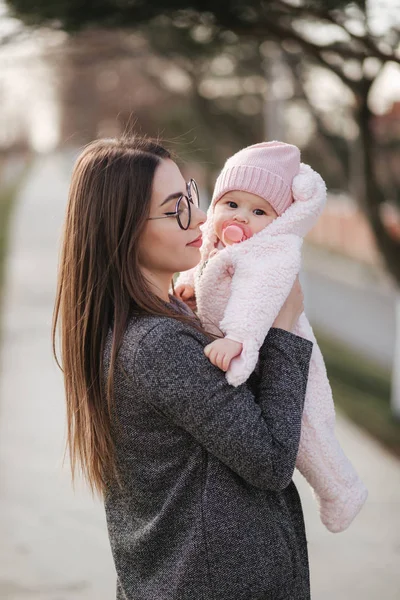 Portret van moeder en haar kleine baby meisje. Mooie moeder en schattige baby. Moeder HUD haar dochter. Baby gekleed in peanch kleur hoed en tepel speelgoed — Stockfoto