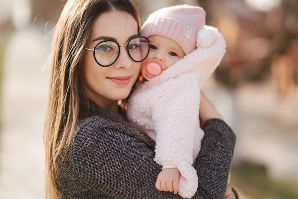 Portrait of mother and her little baby girl. Beautiful mom and cute baby. Mother hud her daughter. Baby dressed in peanch colour hat and nipple toy — Stock Photo, Image