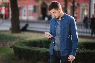 Genç adam sosyal ağda telefon ve kablosuz kulaklıklar ve yazdırma mesajı kullanın