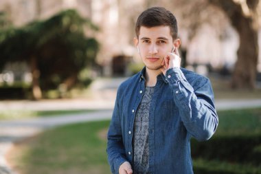 Yakışıklı adam video sohbet için telefon ve kablosuz kulaklıklar kullanın. Görüntülü görüşme