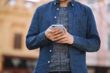 Genç adam sosyal ağda telefon ve kablosuz kulaklıklar ve yazdırma mesajı kullanın. Erkek Blogger