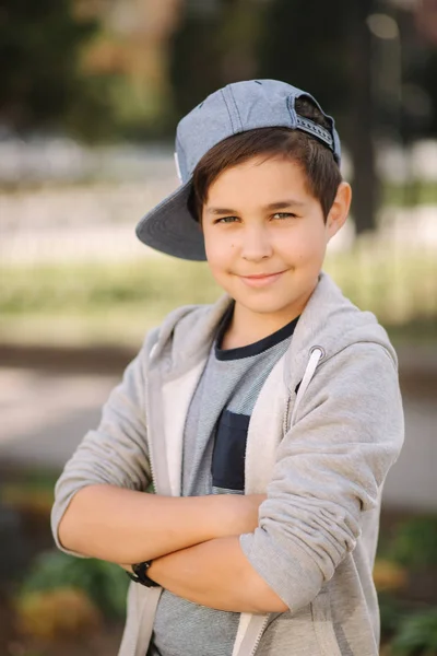 Stylish little school boy in blue cap posing outside for photo. Boy walking in the city in sping summer weather — Stock Photo, Image