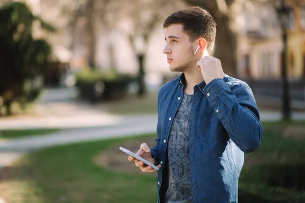 Les jeunes hommes utilisent le téléphone et les écouteurs sans fil et impriment des messages sur les réseaux sociaux — Photo