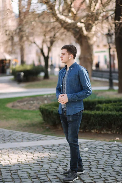 Joven escuchando una música a través de auriculares inalámbricos — Foto de Stock