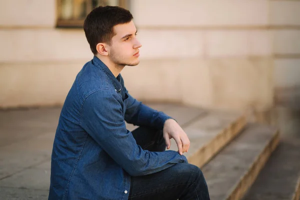 Schöner Mann sitzt auf der Treppe in der Nähe des Parks — Stockfoto