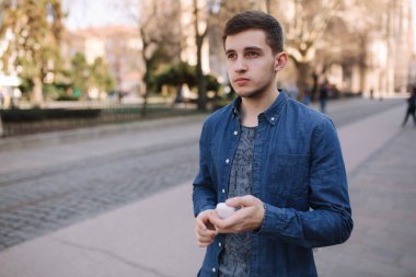 Adam kablosuz kulaklıklarını yerine koydu. Mavi gömlek yakışıklı adam merkezinde stand eğer şehir