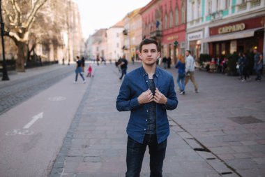 Şehrin merkezinde genç şık adam stand. Adam kablosuz kulaklıklar kullanmak