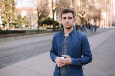 Adam kablosuz kulaklıklarını yerine koydu. Mavi gömlek yakışıklı adam merkezinde stand eğer şehir