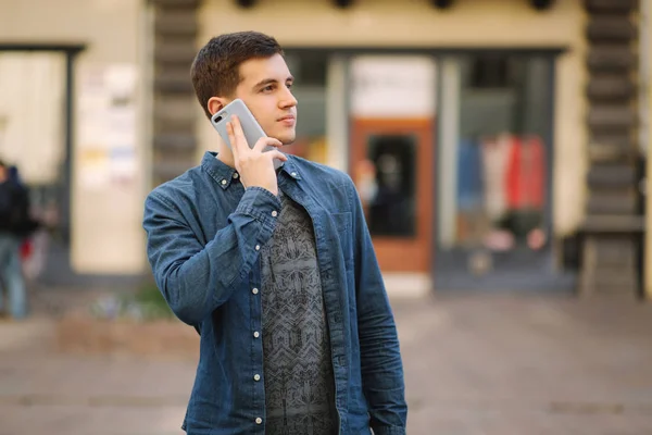 Ung snygg man står i centrum av staden. Man kallar någon — Stockfoto