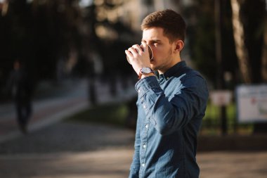 Genç çocuk dışarıda kahve içer. Bahar günbatımı