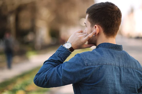 Back view of man usin wireless headphones. Man put his finger on headphone — Stock Photo, Image