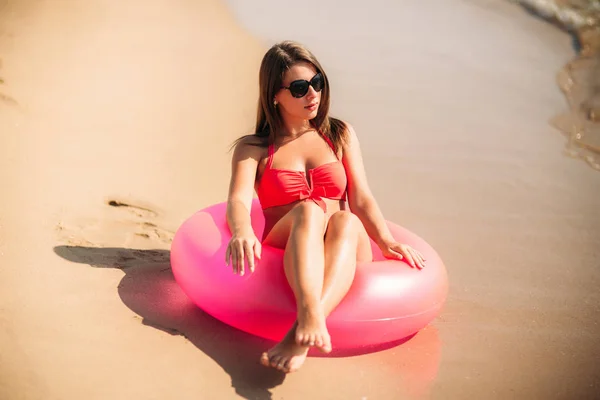 Chica Beautiul sentada en el anillo de agua junto al mar. Chica sexy en traje de baño —  Fotos de Stock