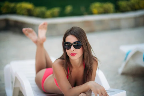Krásná dáma v brýlích leží na slunci před bazénem — Stock fotografie
