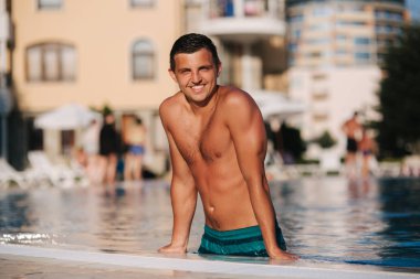 Yakışıklı adam yüzme havuzunun dışında gider. Otel tarafından yüzme yeşil şort genç adam