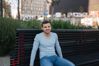 Şehrin merkezinde bankta oturan yakışıklı adam. Dışarıda mutlu adam