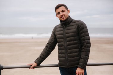 Kuzey Denizi 'nin önünde duran yakışıklı adam. Haki ceket şık adam