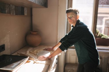 Young man work in his workshop. Handsome guy make an element of decor