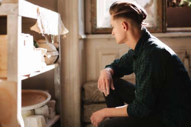 Çömlekçi adam iş için eşya arıyor. Genç adam atölyesinde çömlekçi. Yakışıklı adam işi.