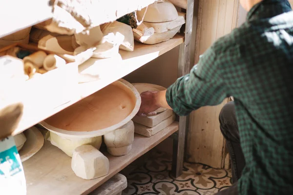 Man keramiker letar efter porslin för ett arbete. Krukmakare i sin verkstad. Snyggt karlarbete — Stockfoto