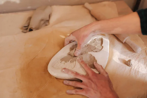 Töpferhände füllen die Form mit einer Keramik in Form eines Schmetterlings. Nahaufnahme der Hände — Stockfoto