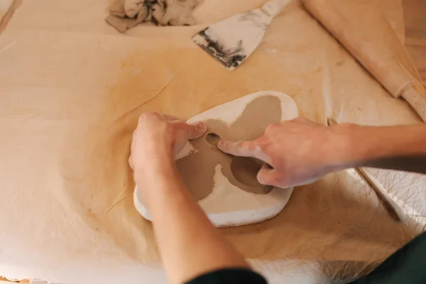 Händerna på en keramiker skapar inslag av dekor med hjälp av en lera. Närbild av manliga händer — Stockfoto