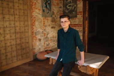 Young man in green shirt in workshop stand by the table