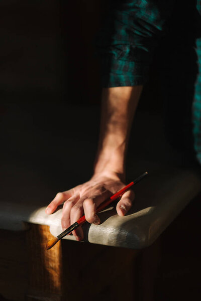 Рука художника с кистью. Солнечные лучи падают на стол и руку
