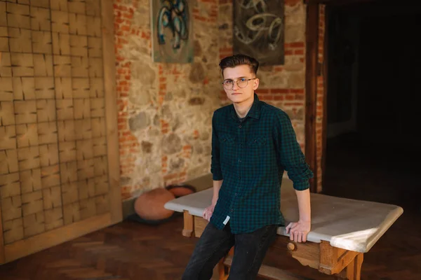 Jeune homme en chemise verte dans le stand de l'atelier à la table — Photo