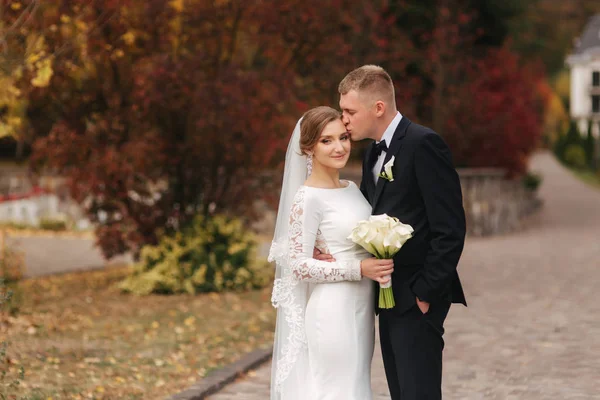 Pareja con estilo wolking en el parque en el día de su boda. Felices recién casados afuera en el clima otoñal — Foto de Stock