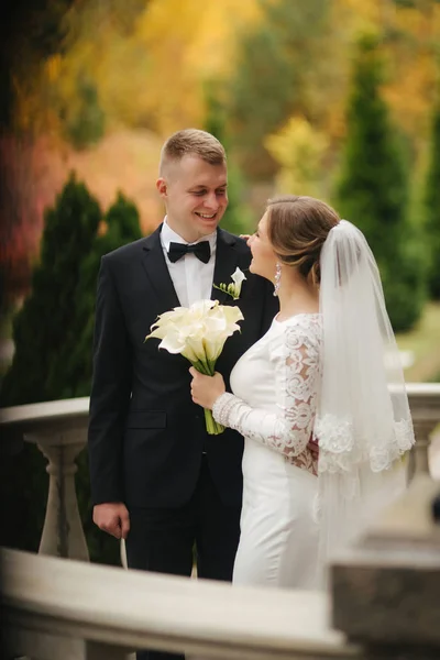 Όμορφο ζευγάρι γάμο σταθεί στο μπαλκόνι. Κομψό νύφη και ο γαμπρός το φθινόπωρο ο καιρός έξω — Φωτογραφία Αρχείου