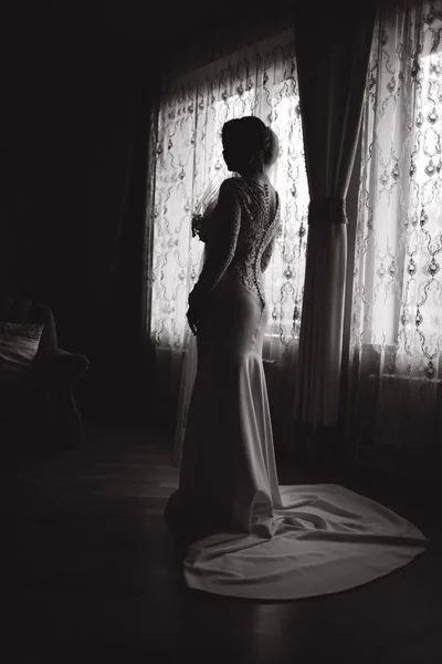 Silhouette of beautiful bride at home standing in front of the window — Stock Photo, Image