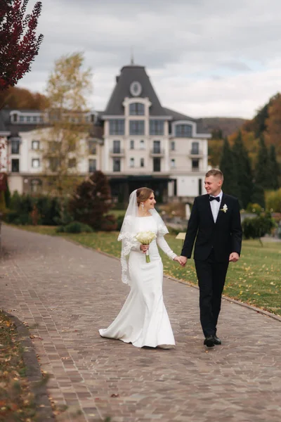 Casal elegante wolking no parque em seu dia do casamento. Feliz recém-casados fora em clima de outono — Fotografia de Stock