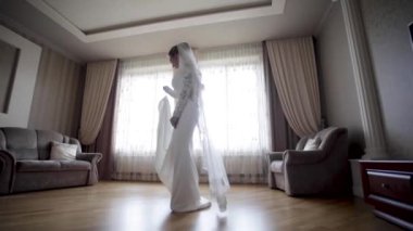 Güzel gelin evde gelinlik etrafında spin. Büyük pencerenin arka planı